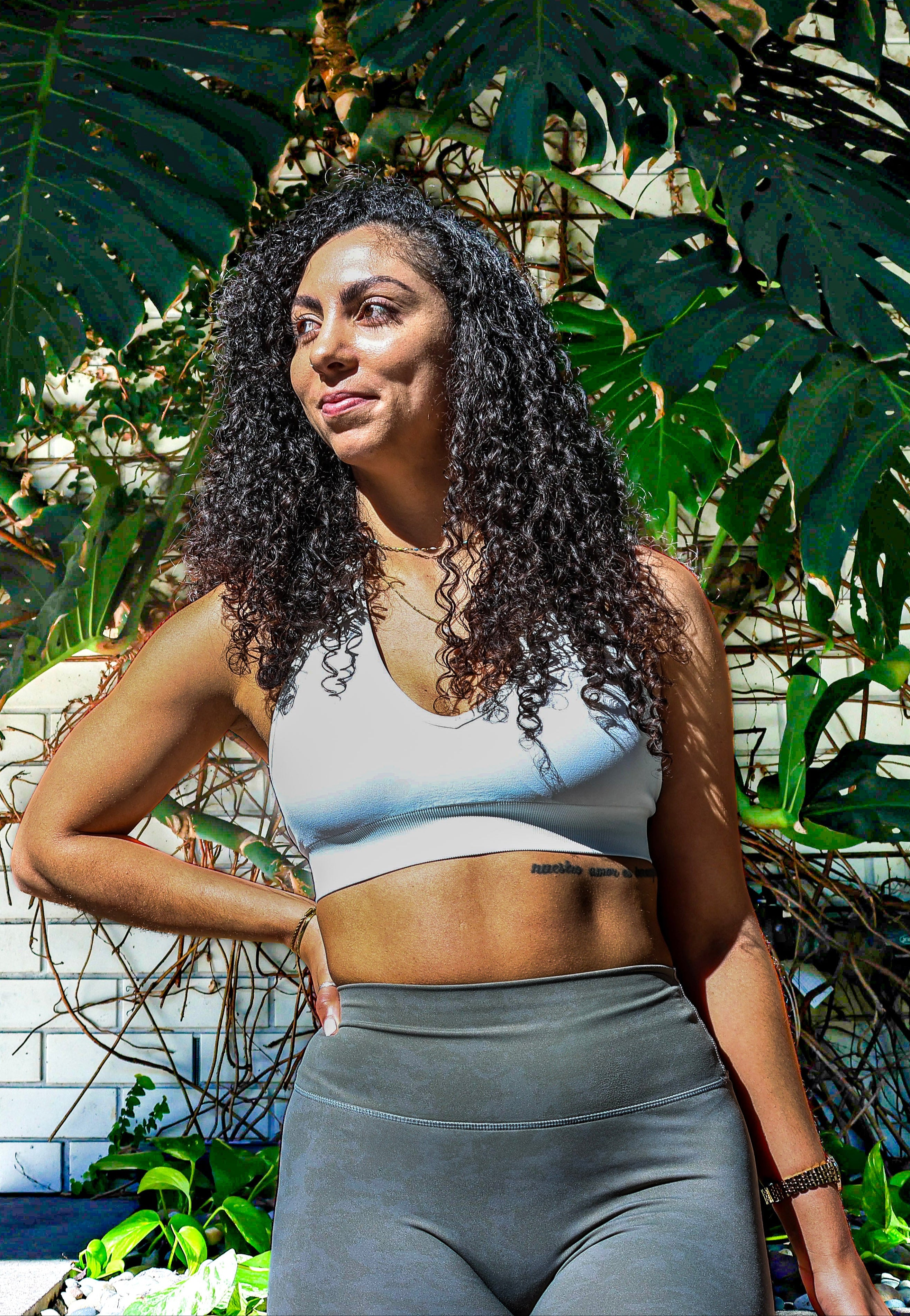 Woman in athletic wear standing among tropical plants